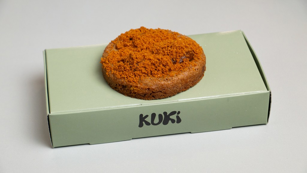 A crumb-topped Kuki cookie on its box